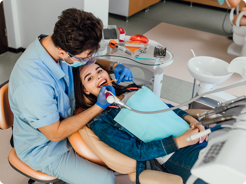 Dentist performing a checkup on a smiling patient in a dental chair.