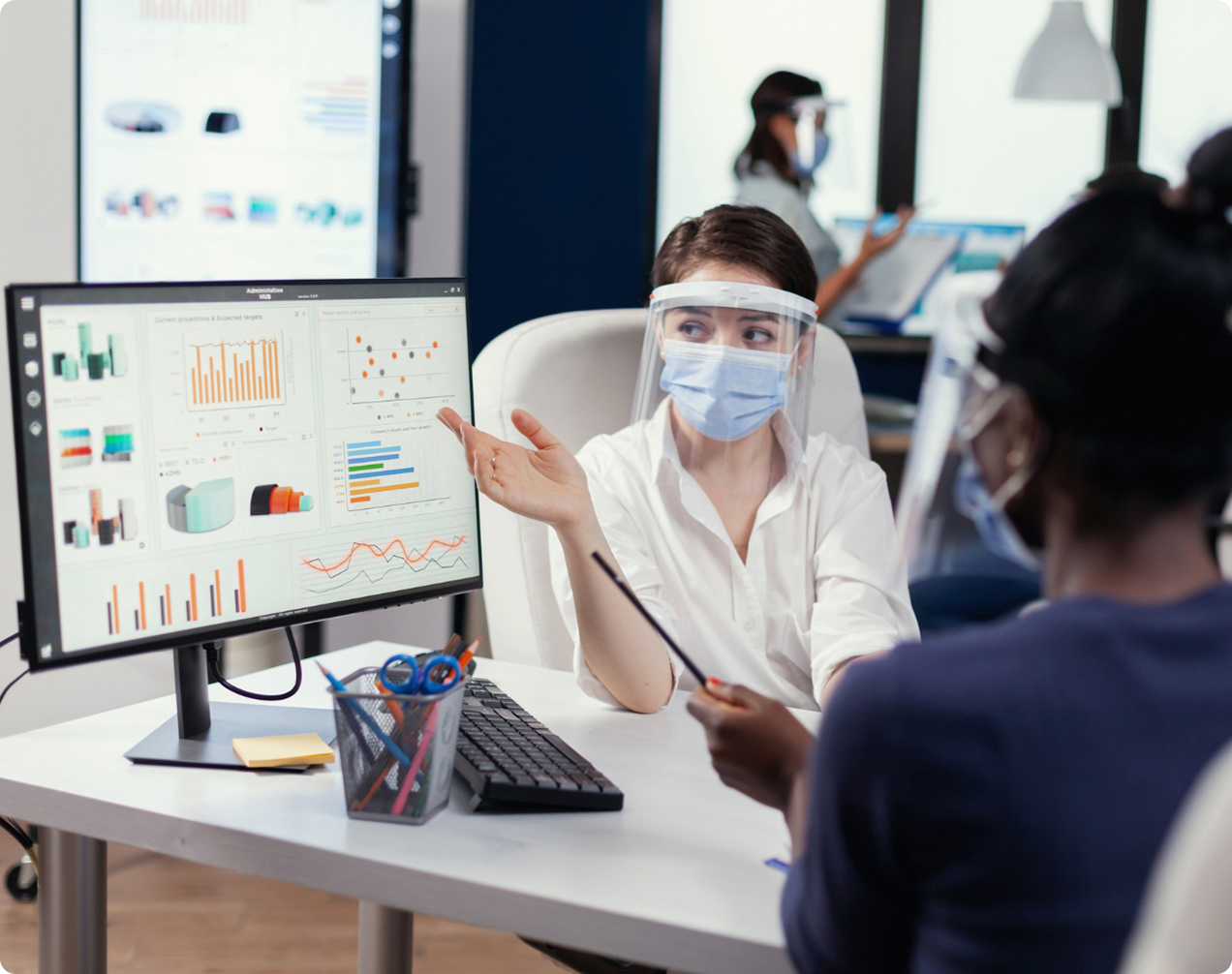 Healthcare professionals in a meeting reviewing data charts on a computer screen.
