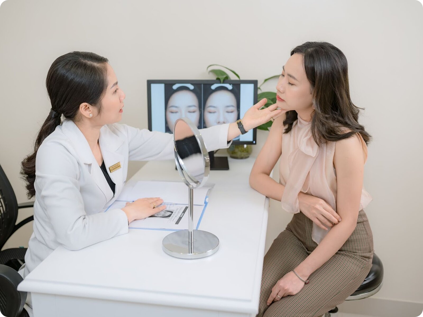 A female dermatologist in a white coat consulting with a patient in a modern clinic office.