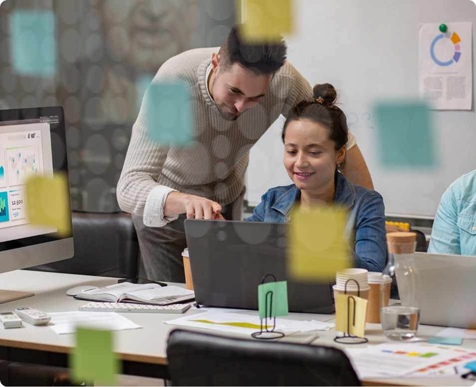 Two marketing professionals collaborating over a laptop in a modern office, reviewing data analytics and healthcare marketing strategies.